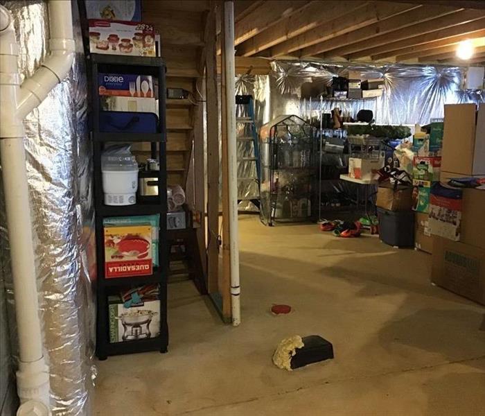 dried unfinished basement, with toys and storage totes put back onto shelves